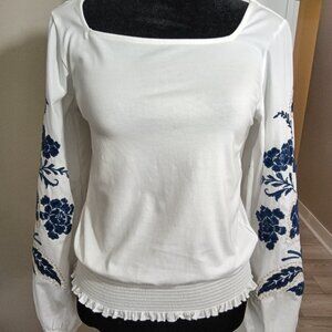 A preowned unique white peasant top with full floral embroidered sleeves